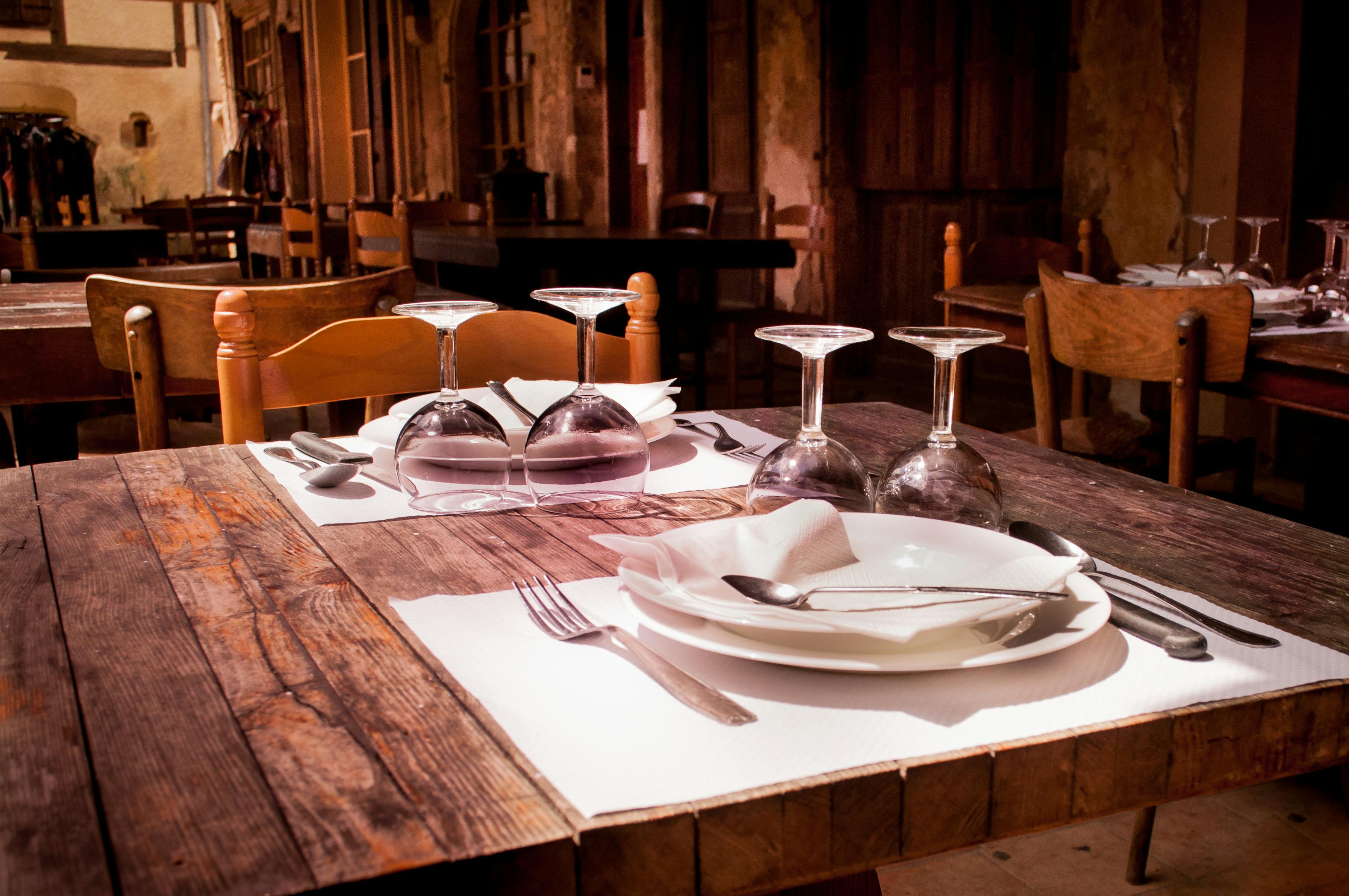A rustic restaurant table set with wine glasses and cutlery invites guests to dine.